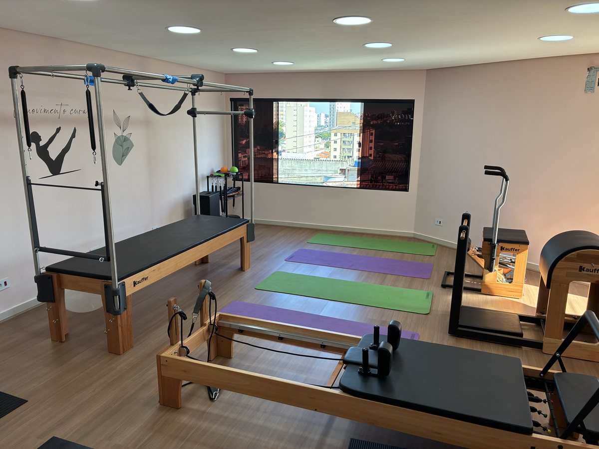 Reformers de pilates alinhados na sala de piso de madeira